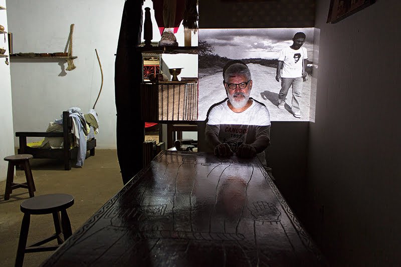Padre Enoque em 2016 com foto de 1989 projetada sobre ele. Foto feita na sua casa em Euclide da Cunha.